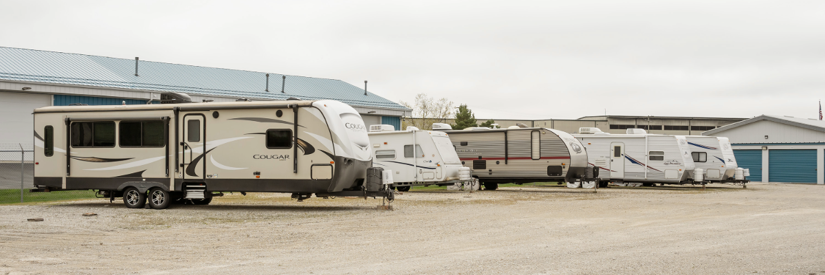 Row of travel trailers and campers parked in the outdoor RV storage lot near Wind Lake and Waterford, WI