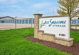 AllSeason_011a All Seasons Storage monument sign with storage unit buildings and fenced lot visible on both sides